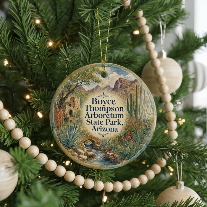 A round ornament hanging on a Christmas tree, featuring a desert landscape with mountains and cacti.