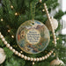 A round ornament hanging on a Christmas tree, featuring a desert landscape with mountains and cacti.