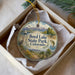 A decorative ornament in a box, featuring a scenic landscape with mountains, a lake, and various wildlife elements.
