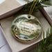 A decorative ornament in a box, featuring a scenic image of Buckhorn Lake State Resort Park, Kentucky.