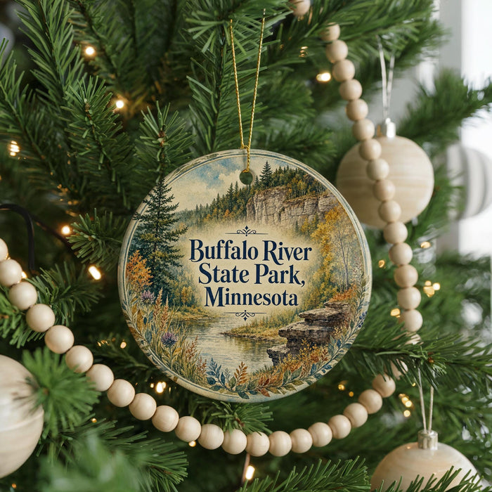 A round ornament hanging on a Christmas tree, featuring a scenic image of the buffalo river and buffalo in the background.
