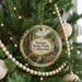 A round ornament hanging on a Christmas tree, featuring a scenic landscape with a waterfall and pine trees.