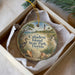 A decorative ornament in a box, featuring a beach scene with a lighthouse and palm trees, along with the text "Caladesi Island State Park, Florida".