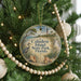 A round ornament hanging on a Christmas tree, featuring a beach scene with a lighthouse and palm trees.