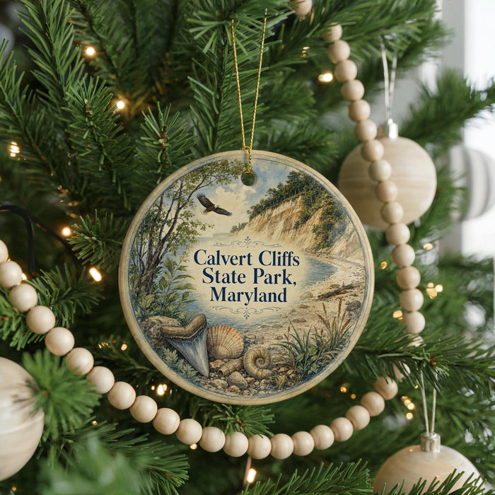 A round ornament hanging on a Christmas tree, featuring a scenic landscape with a cliff, river, and wildlife.