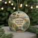 A round ornament with a painting of a beach and palm trees, featuring the text "Camp Helen State Park, Florida" on it.