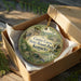 A decorative ornament in a wooden box, featuring a scenic image of the Carter Caves State Resort Park in Kentucky.