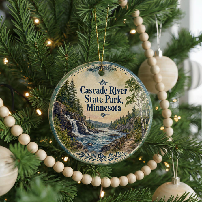 A round ornament hanging on a Christmas tree, featuring a scenic image of the Cascade River State Park in Minnesota.