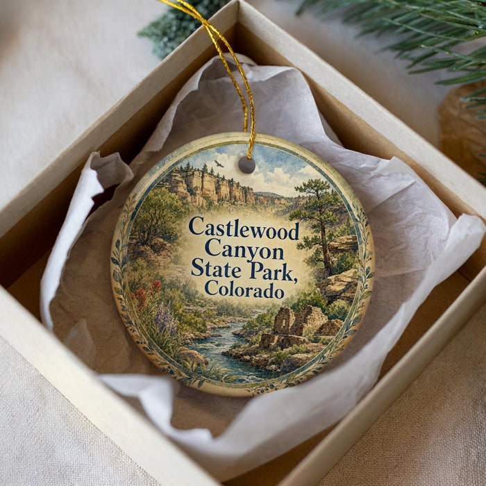 A round ornament with a scenic image of Castlewood Canyon State Park, Colorado, displayed in a box.