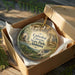 A decorative ornament in a cardboard box, featuring a scenic image of the Cathedral Caves in Alabama.