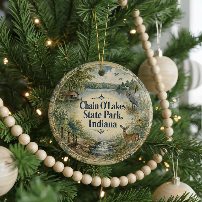 A round ornament hanging on a Christmas tree, featuring a scenic image of Chain O Lakes State Park, Indiana.