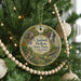 A round ornament hanging on a Christmas tree, featuring a scenic image of a waterfall and a bird.