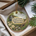 A round ornament with a scenic image of Clark Creek, surrounded by greenery, is displayed in a box with pine branches.
