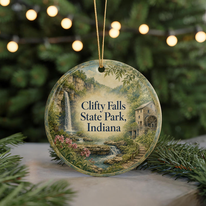 A round ornament with a painting of Clifft Falls State Park, Indiana, hanging from a string.