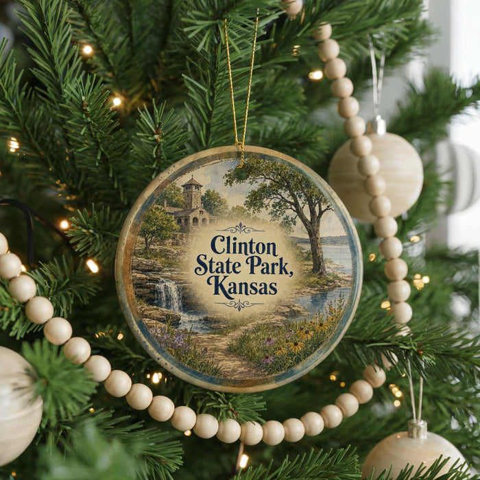 A round ornament hanging on a Christmas tree, featuring a scenic landscape with a waterfall and trees.