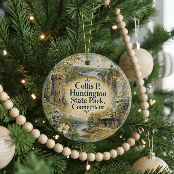 A round ornament hanging on a Christmas tree, featuring a scenic landscape with a castle, trees, and a river.