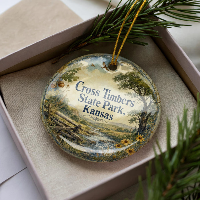 A decorative ornament in a box, featuring a scenic landscape with a river, trees, and flowers.