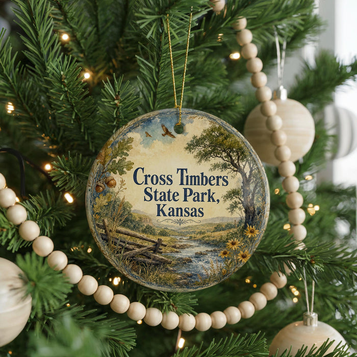 A round ornament hanging on a Christmas tree, featuring a scenic landscape with a river and trees.