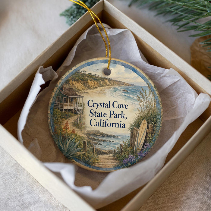 A decorative ornament in a white box, featuring a scenic image of Crystal Cove State Park, California.
