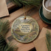 a decorative ornament with a painting of a windmill and a rural landscape, placed on a table next to a cup of coffee.