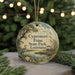 A round ornament with a painting of a bird, a pond, and a gazebo, hanging from a string.