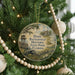 A round ornament hanging on a Christmas tree, featuring a scene from Battlefield Historic State Park, Florida.