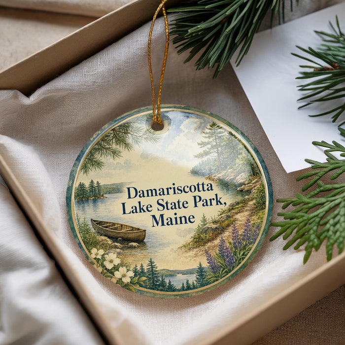 A decorative ornament with a lake scene and a boat, hanging from a string.