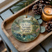 A decorative ornament featuring a scenic image of De Leon Springs State Park, Florida, with a candle and pine cones on a wooden tray.