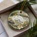 A decorative ornament with a scenic image of Delta Heritage Trail State Park in Arkansas, featuring a river, a house, and other natural elements.