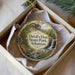 A decorative ornament in a box, featuring a scenic landscape with a waterfall and lush greenery.