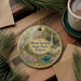 A decorative ornament featuring a scenic image of Dixon Springs State Park in Illinois, with a waterfall and a house in the background. The ornament is hanging on a wooden surface, surrounded by pine branches and a cup of coffee.