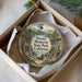 A decorative ornament in a box, featuring a scenic landscape with mountains, a cabin, and a wagon, along with the text "Donner Memorial State Park, California".