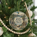 A round ornament hanging on a Christmas tree, featuring a scenic illustration of Donner Memorial State Park in California.