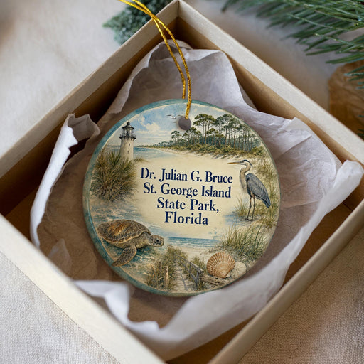A round ornament with a lighthouse and beach scene, featuring text that reads "Dr. Julian G. Bruce St. George Island State Park, Florida".