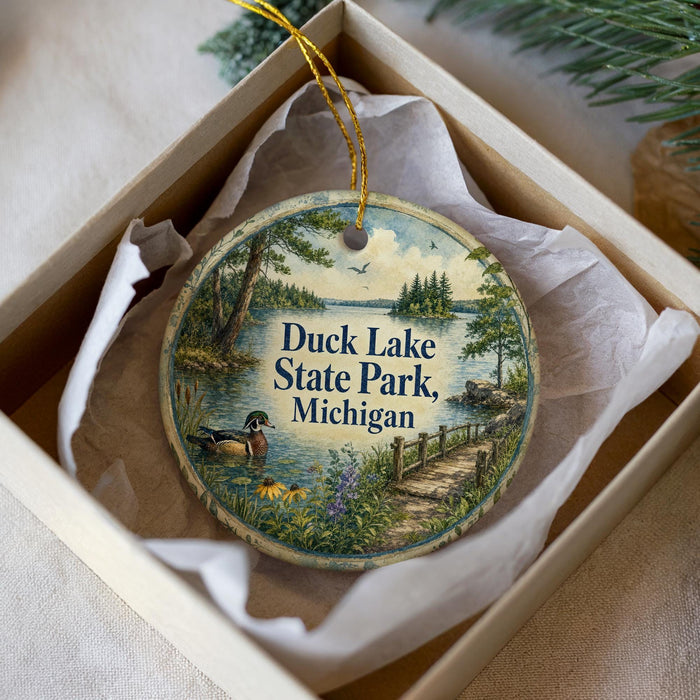 A decorative ornament in a box, featuring a scenic image of Duck Lake State Park in Michigan.