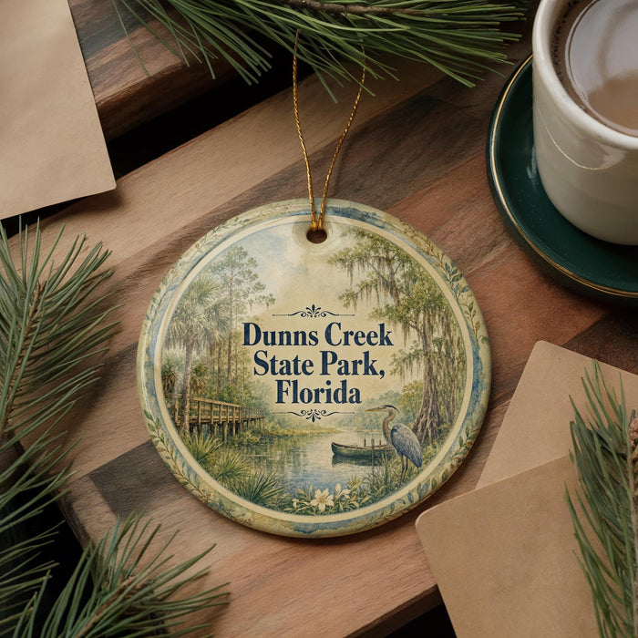 A decorative ornament featuring a scenic image of Dunns Creek State Park in Florida, with a bird and a boat in the foreground.