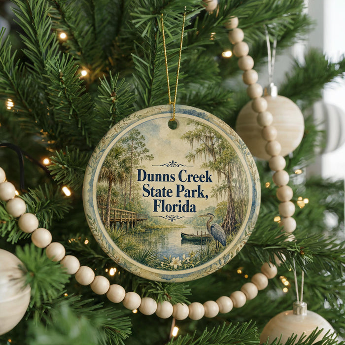 A round ornament hanging on a Christmas tree, featuring a scenic image of Dunn's Creek State Park in Florida.