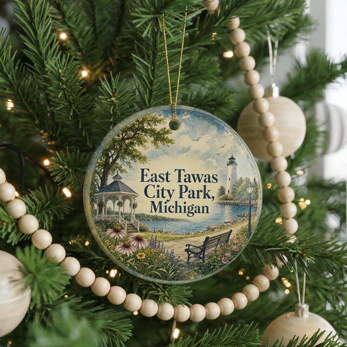 A round ornament hanging on a Christmas tree, featuring a scenic view of East Tawas City Park in Michigan.