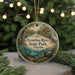 A circular ornament with a scenic image of the Econfina River State Park in Florida, featuring a bird, palm trees, and a winding path.