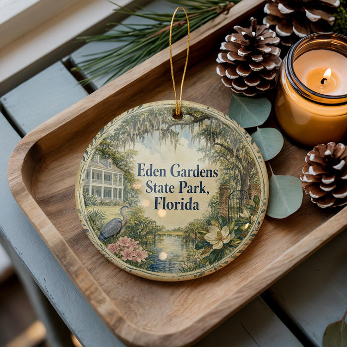 A decorative ornament with a scenic image of Eden Gardens State Park, Florida, is displayed on a wooden tray alongside pine cones and a lit candle.