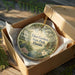 A decorative ornament in a box, featuring a scenic image of Eden Gardens State Park, Florida.