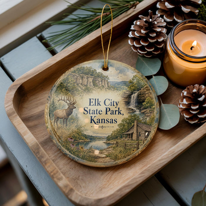 A wooden tray with a decorative ornament featuring a scenic landscape of Elk City State Park, Kansas, along with pine cones and a lit candle.