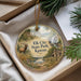A decorative ornament with a scenic landscape of a river, mountains, and a deer, hanging from a string.