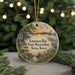 A round ornament with a scenic landscape featuring a lake, trees, and birds, hanging from a string.