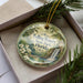 A decorative ornament in a box, featuring a scenic image of Falling Waters State Park in Florida.