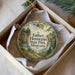 A round ornament with a scenic illustration of Hennepin State Park in Minnesota, featuring a waterfall and a house, is displayed in a box.