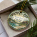 A round ornament with a scenic landscape of Faver-Dykes State Park, Florida, featuring a bird, a cabin, and a body of water.