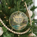A round ornament hanging on a Christmas tree, featuring a scenic image of Faver-Dykes State Park, Florida.
