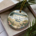 A decorative ornament in a box, featuring a beach scene with a bird and flowers, and the text "Ferry Beach State Park, Maine".