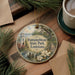 A decorative ornament featuring a scenic image of Fondahebeau State Park in Louisiana, with a bird and flowers in the foreground.